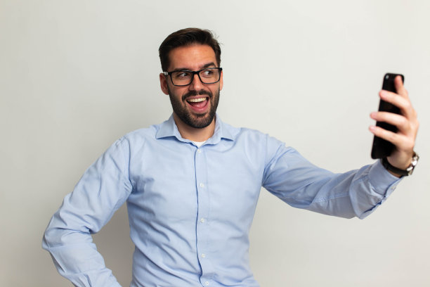 英俊的男子，手机在灰色背景图片下载