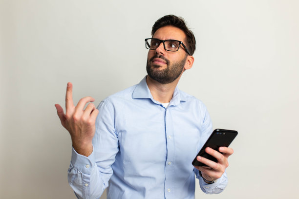 英俊的男子，手机在灰色背景图片下载