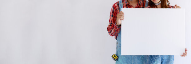 年轻的亚洲夫妇在礼服格纹衬衫和熊布与橙色帽子显示白板在手上图片下载