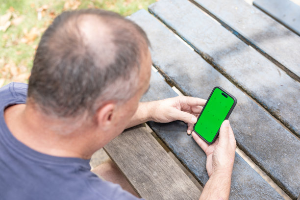 中年男子，手机上有绿色屏幕图片下载