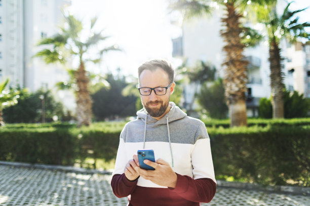 年轻的成年男子在街上使用手机应用程序图片下载