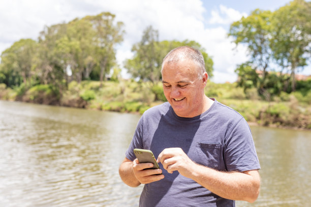 中年男子在河边用手机网购图片下载