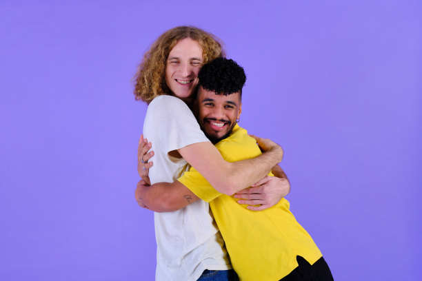 中间的照片是两个英俊的朋友在紫色的演播室背景下微笑着拥抱彼此图片下载