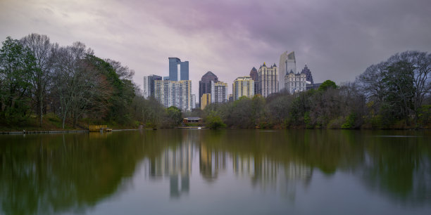 美国佐治亚州首府皮埃蒙特公园的克拉拉米尔湖上的亚特兰大市天际线、摩天大楼、建筑、森林和水的倒影，柔和柔和的色彩，长曝光照片图片下载