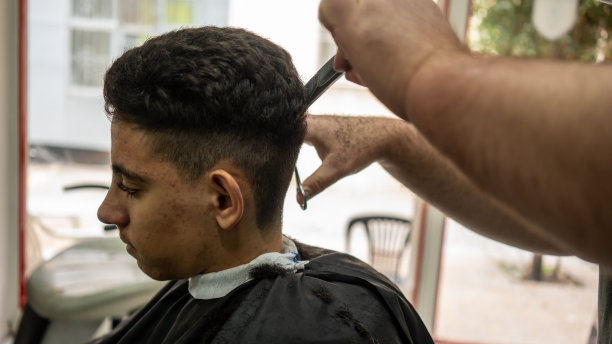 理发师正在理发店剪男孩的头发图片下载