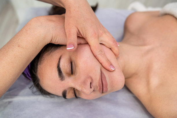 按摩师的手做放松按摩女性面部在水疗沙龙图片下载