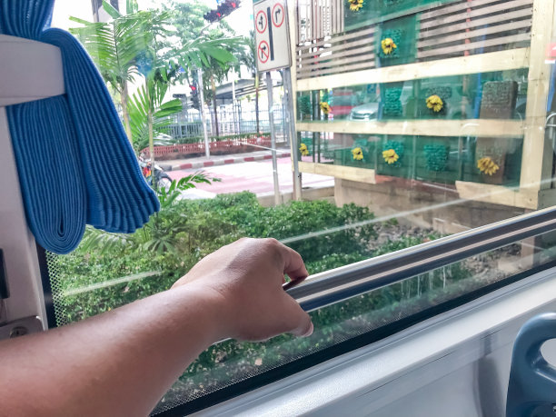 后视图左手握着公共汽车内的扶手，通过窗户看到的公共交通。图片下载