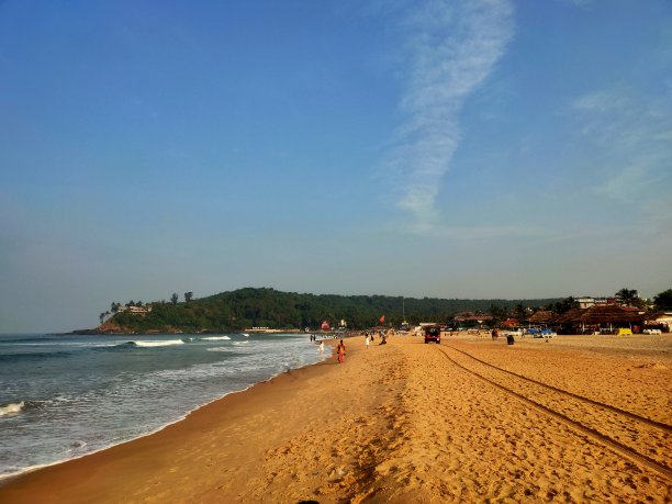 在海滩海浪的边缘，沙子上有一辆救援吉普车的轮胎印图片下载