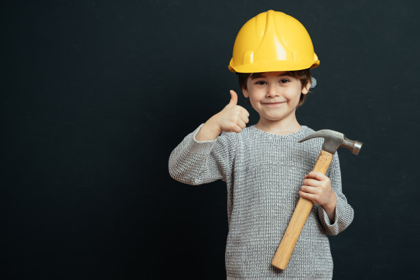 小工作男孩的肖像，戴着黄色安全帽图片下载