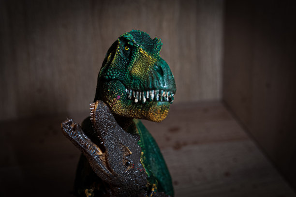一个绿色眼睛的恐龙玩具的特写图像图片下载