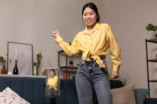 欢快的亚洲女子在镜头前跳舞，用手机拍摄视频图片下载