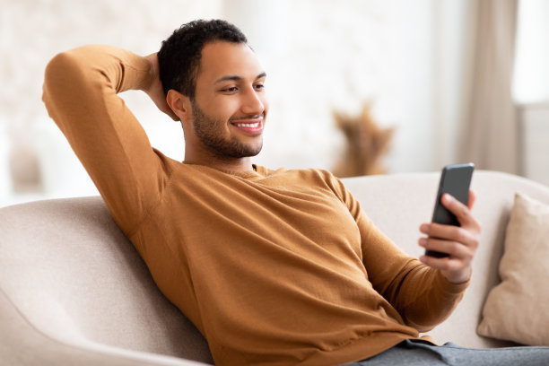 在家使用智能手机的微笑阿拉伯男人肖像图片下载