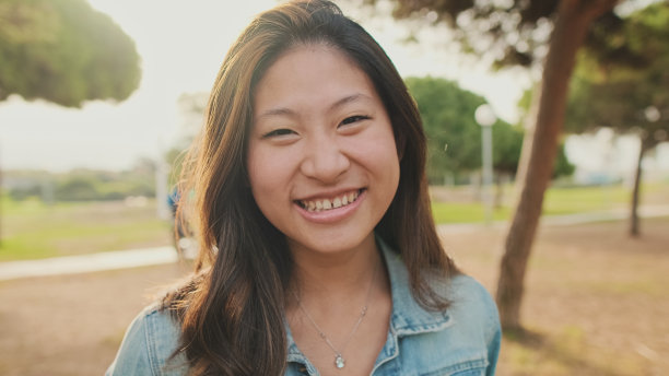 特写，年轻女子站在公园里对着镜头摆姿势。看着镜头图片下载