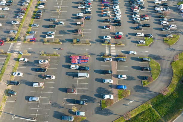 许多五颜六色的汽车停在停车场上的鸟瞰图，上面有停车地点和方向的线条和标记图片下载