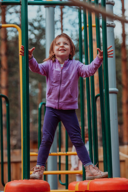 一个小女孩在公园里玩。公园家庭社交的概念。一个女孩在荡秋千，玩创意游戏图片下载