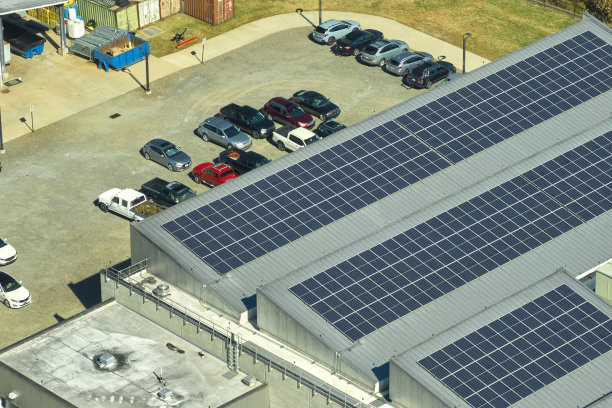 蓝色光伏太阳能电池板安装在工业建筑屋顶生产绿色生态电力鸟瞰图。生产可持续能源的概念图片下载