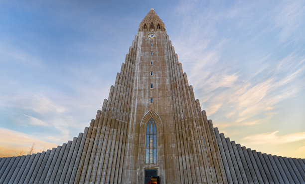 从下面对称地看到Hallgrímskirkja大教堂的极简主义建筑，基于冰岛的玄武岩地层，被黎明的第一缕曙光照亮。图片下载