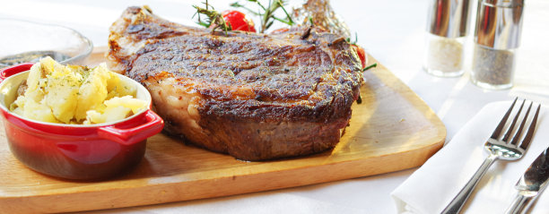 厚烤骨肋眼牛排配番茄和土豆泥，放在木托盘上。图片下载