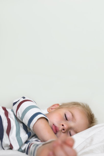 小孩睡在白色光滑的毯子上。小3岁的孩子独自睡在舒适的卧室。柔软的纺织品。昏昏欲睡的金发婴儿男孩在家里的床上做梦。为横幅签名。文本空间图片下载