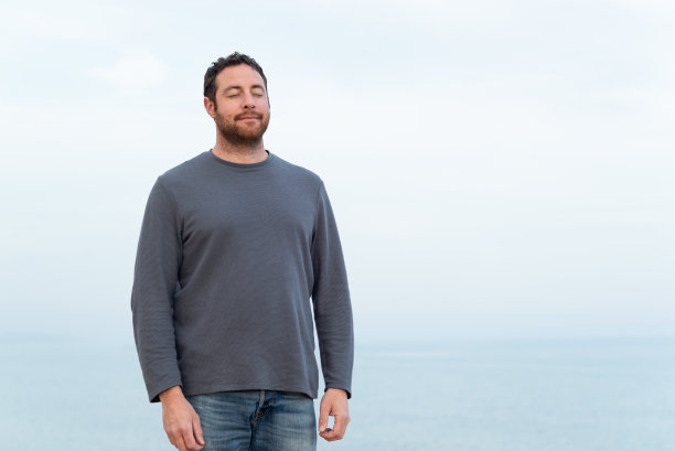 一个放松的人的肖像闭上眼睛和大海的背景。图片下载