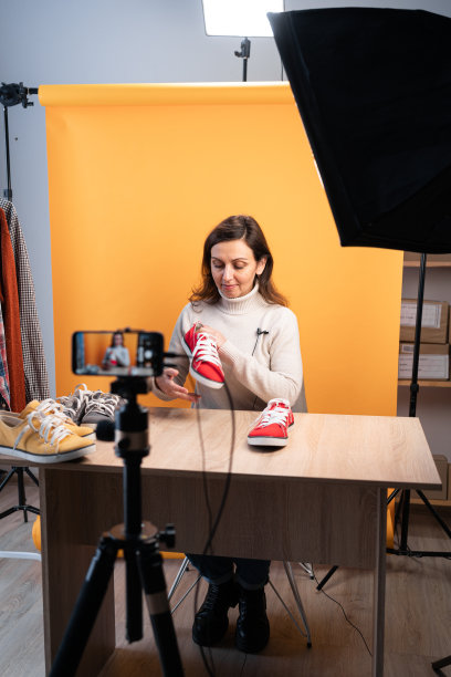 西班牙裔女博主看着手机相机审查产品。现代女商人使用社交媒体进行营销，拥有网上商店。社交媒体上的商业在线影响者图片下载