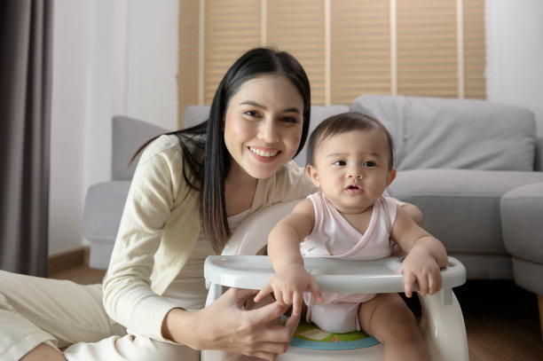年轻的妈妈在婴儿椅上帮助婴儿吃混合食物图片下载