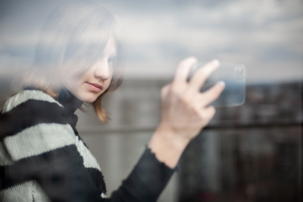 城市里有影响力的少女，靠窗，用智能手机图片下载