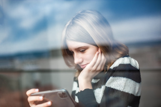 城市里有影响力的少女，靠窗，用智能手机图片下载