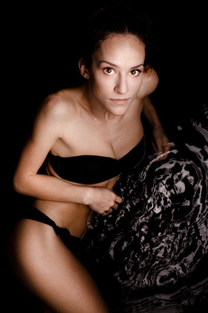 美丽的白人女孩在泳装躺在水面上的反射。图片下载