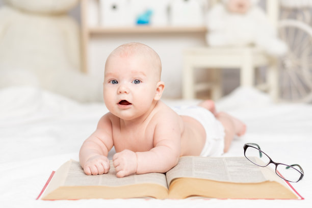 男婴带着一本大书和一副眼镜在托儿所学习和发展概念图片下载