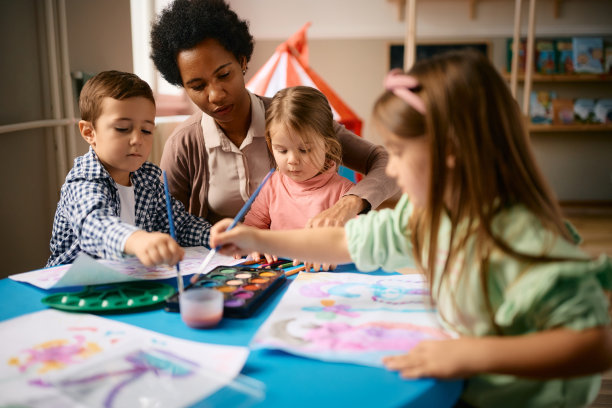 黑人女老师和一群孩子在学前班的美术课上涂色。图片下载