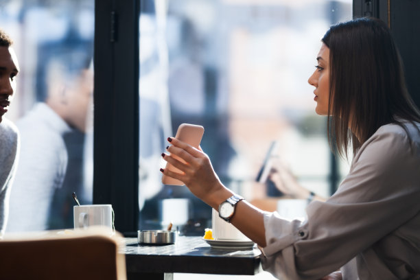 朋友们在餐厅里微笑着聊天，用手机展示照片。下班后在咖啡馆酒吧开会的商务同事。图片下载
