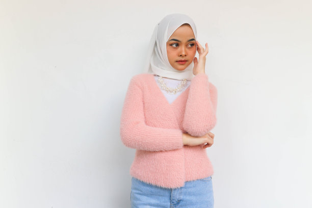 年轻的亚洲穆斯林妇女穿着粉红色运动上衣的肖像，看着白色背景上孤立的复制空间图片下载