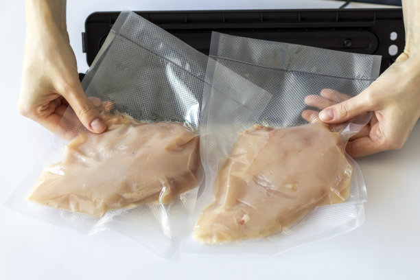 一袋袋生鸡胸肉放在一个包装工面前，一个女人手里放在一张白色的桌子上图片下载