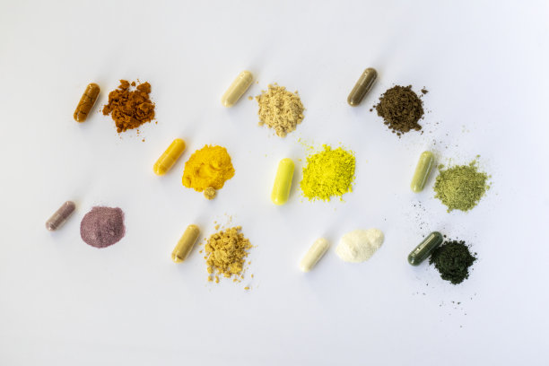 白色背景的打开的和完整的补充剂胶囊。各种药片和维生素。从右到左依次为:姜黄素、维生素C、蚂蚁树皮、槲皮素、q10、蔬菜补品、白藜芦醇、生姜、酶、螺旋藻。图片下载