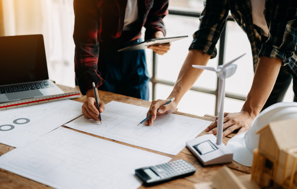 在现代城市的建筑工地上，工程师团队开会一起工作，戴着工人头盔和安全帽。亚洲行业专业团队图片下载