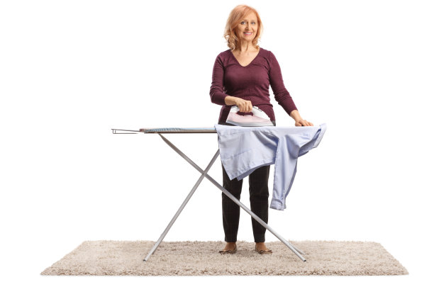 成熟的女人在熨衬衫，面带微笑图片下载