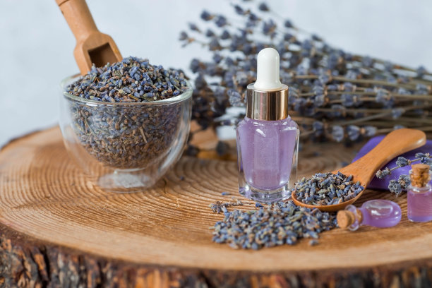 芳香疗法。按摩和水疗。化妆品瓶薰衣草精油，干花和薰衣草种子放在一个木架上。天然的身体化妆品。图片下载