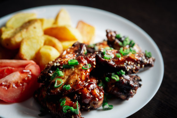 烤鸡翅配芝麻和青葱，配土豆和番茄图片下载