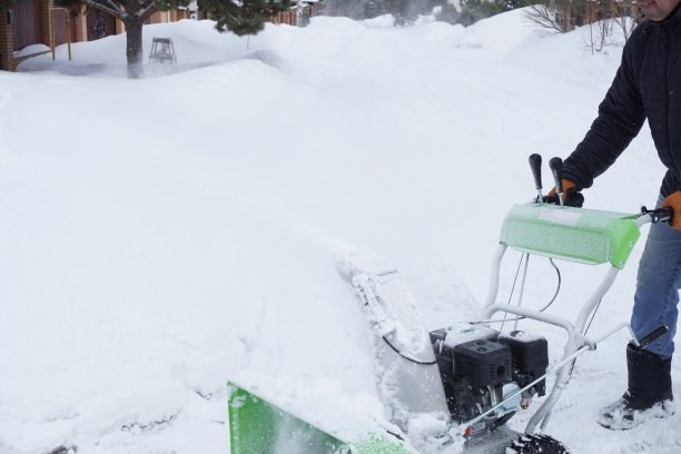 冬天，一名男子在房子的院子里清理积雪，他用吹雪机清理积雪图片下载