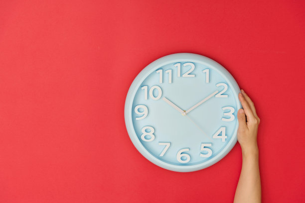 人手拿着红色背景上的时钟图片下载