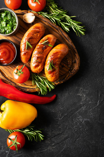 在船上烧烤和烧烤香肠，黑色背景上有酱汁、西红柿和迷迭香图片下载