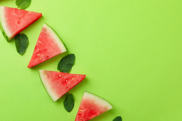 多汁的西瓜片和叶子在绿色的背景图片下载