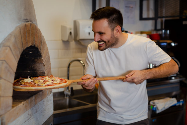 厨师把木头放进烤箱。用于烹饪和烘焙意大利传统披萨的柴火烤箱图片下载