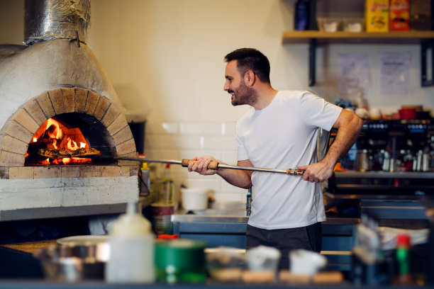 厨师把木头放进烤箱。用于烹饪和烘焙意大利传统披萨的柴火烤箱图片下载