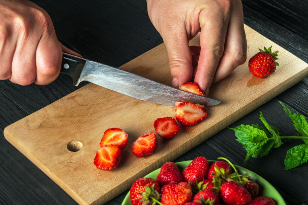 特写:厨师在餐厅厨房的砧板上切新鲜草莓，用来制作薄荷饮料。烹饪减肥甜点图片下载