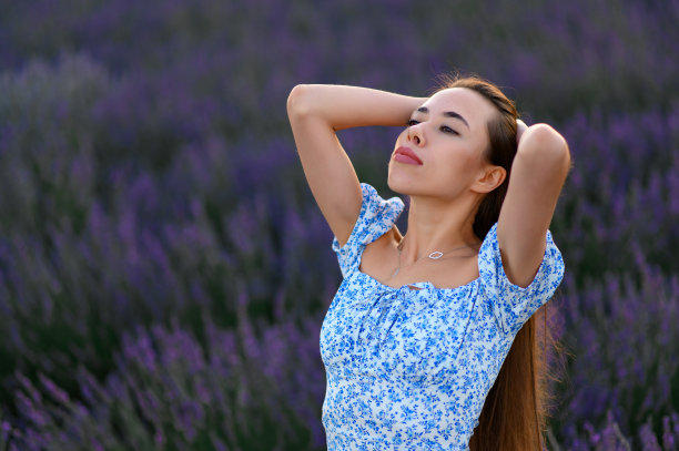 迷人的苗条快乐的女孩在薰衣草田在日落的蓝色连衣裙。图片下载