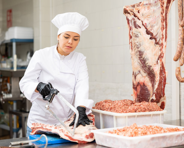 微笑的女屠夫在肉铺里锯着大块的牛肋骨图片下载