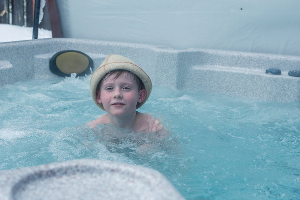 在寒冷的冬日，快乐快乐的家庭带着孩子在按摩浴缸的漩涡中享受热水浴。图片下载