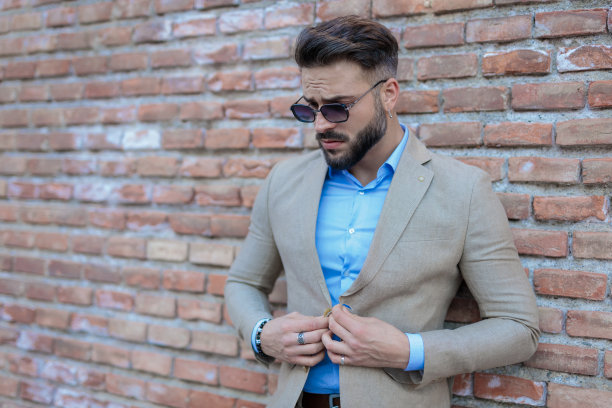 性感的大胡子男人，戴着墨镜，扣着西装，向下看图片下载